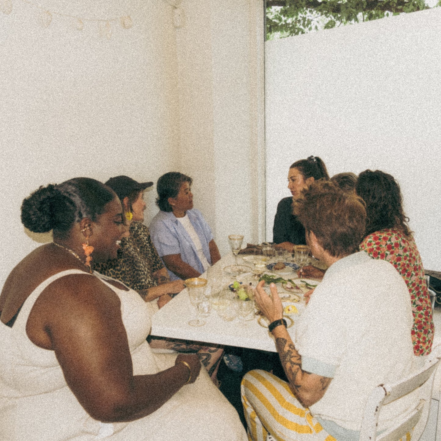 Group of women sitting around a table outdoors, engaged in conversation.