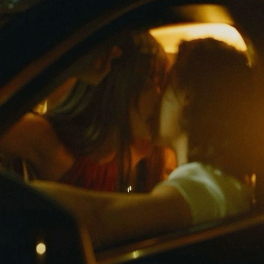 Two women kissing in a car at night 
