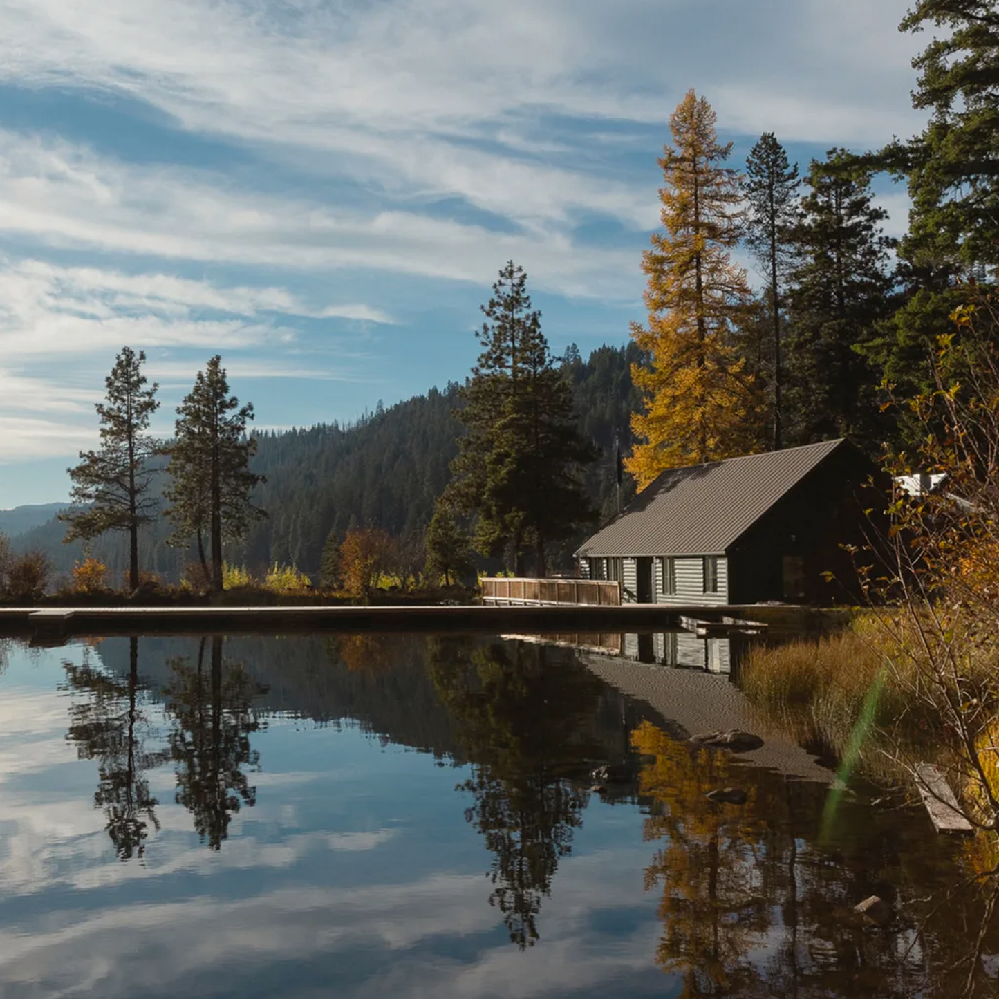 Cabin by a lake with trees reflecting on the water